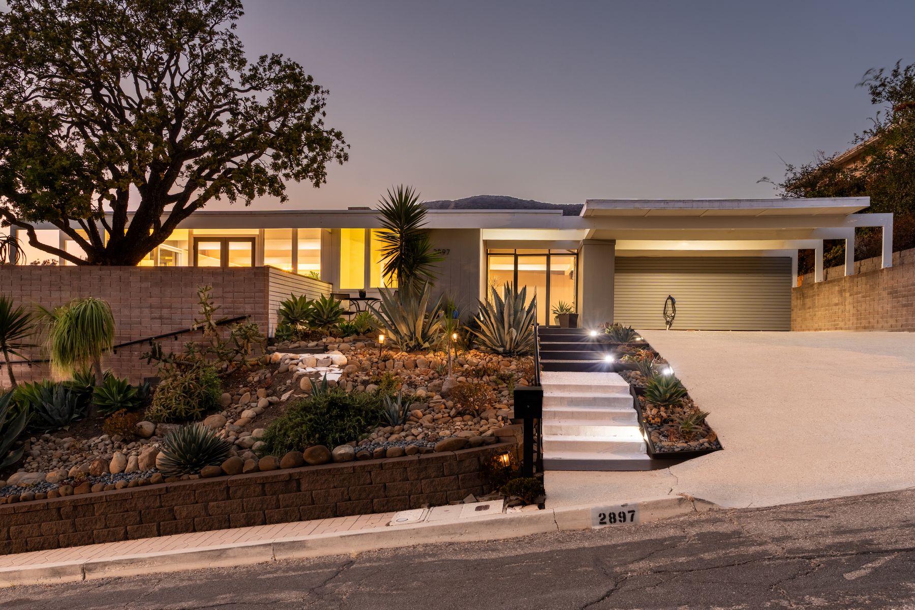 The Addison Residence at twilight, with warmly illuminated windows, its broad horizontal roofline and landscaped approach