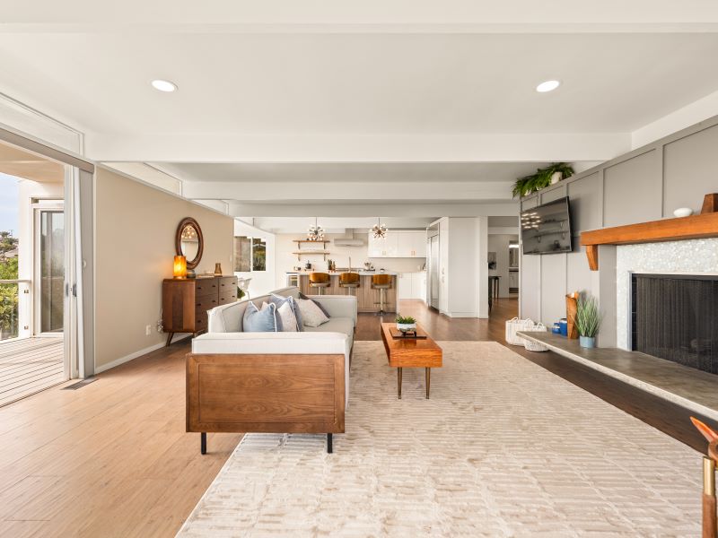 Open living room with exposed ceiling beams, fireplace and extensive glazing